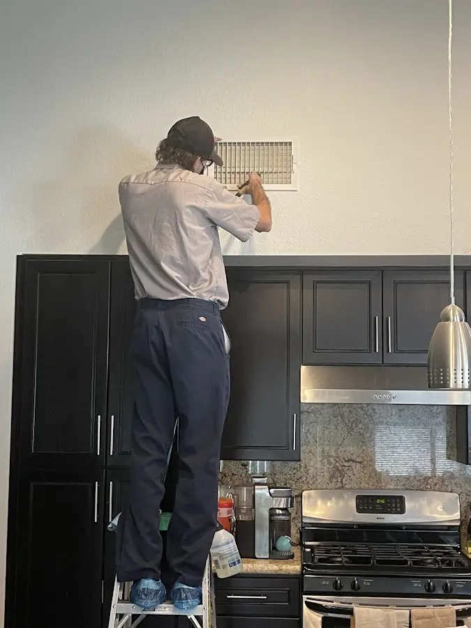 Technician inspecting an air vent during HVAC service in Waterford